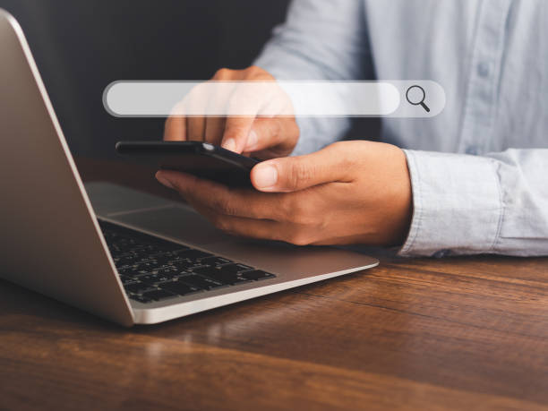 istock Close-up of hand a man using a mobile phone with a laptop for searching information on a web browser. 1485722069