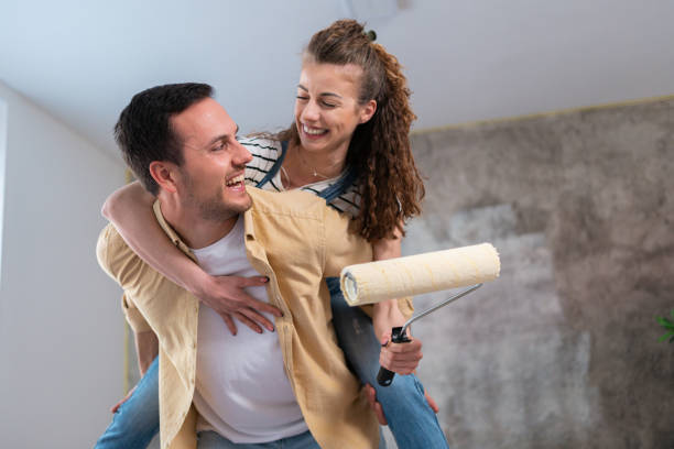 pareja caucásica, divirtiéndose mientras renueva su nuevo apartamento - home improvement couple painting real estate fotografías e imágenes de stock