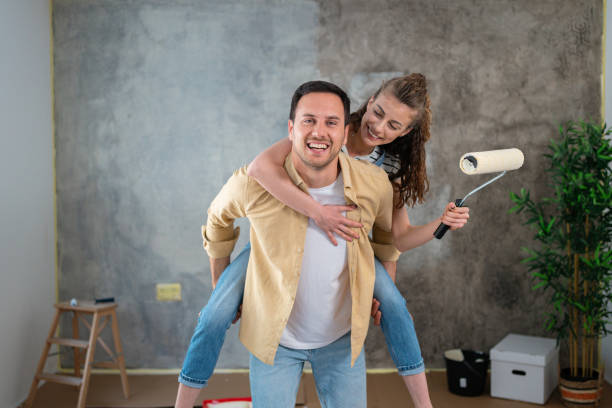 pareja joven, divirtiéndose mientras renueva su nuevo apartamento - home improvement couple painting real estate fotografías e imágenes de stock