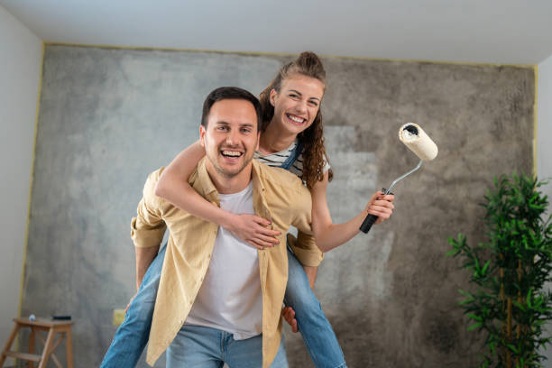 pareja joven, divirtiéndose mientras renueva su nuevo apartamento - home improvement couple painting real estate fotografías e imágenes de stock