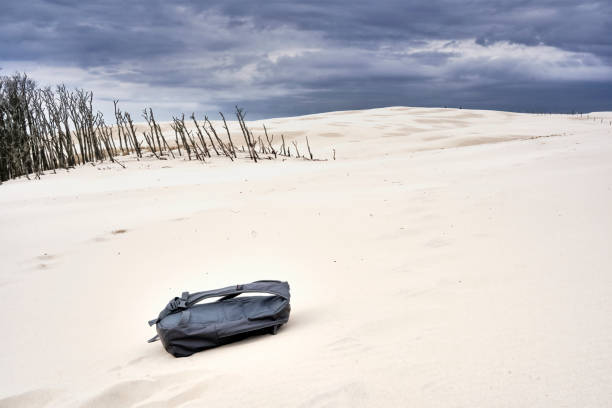 ポーランドのレバ島の砂丘を移動し、前景に紛失したバックパック - bizarre landscape sand blowing ストックフォトと画像