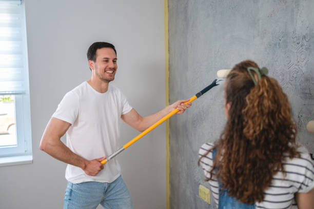 pareja caucásica pintando la pared de su nuevo apartamento - home improvement couple painting real estate fotografías e imágenes de stock