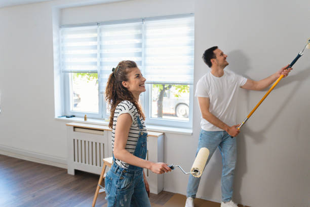 pareja caucásica pintando la pared de su nuevo apartamento - home improvement couple painting real estate fotografías e imágenes de stock