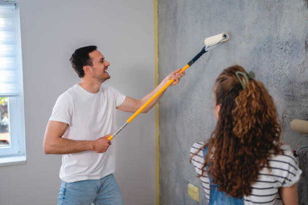 pareja caucásica pintando la pared de su nuevo apartamento - home improvement couple painting real estate fotografías e imágenes de stock