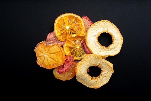 Dried fruit slices isolated on a black background. Dried orange, apple, strawberry, apricot and persimmon slice, top view.