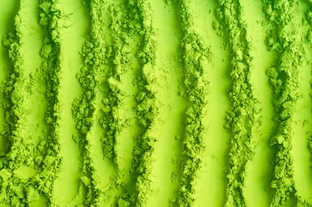 Photo of Green tea matcha powder texture close up, selective focus. Abstract background with brush strokes.