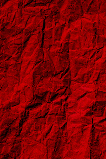 Wrinkled red paper texture background photo. Crumpled paper surface for designs.