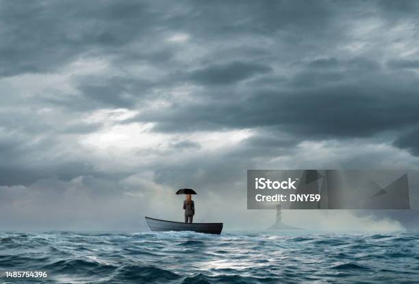 Businesswoman Holding Umbrella Looks At Lighthouse While Stranded On Boat Stock Photo - Download Image Now