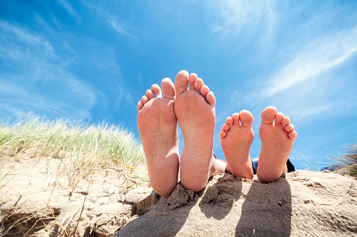 Family feet relaxing and sunbathing in sand on the beach concept for vacation and summer holiday