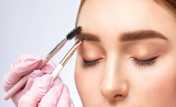 The make-up artist does Long-lasting styling of the eyebrows of the eyebrows and will color the eyebrows. Eyebrow lamination. Professional make-up and face care. The make-up artist does Long-lasting styling of the eyebrows of the eyebrows and will color the eyebrows. Eyebrow lamination. Professional make-up and face care. hand tinted stock pictures, royalty-free photos & images