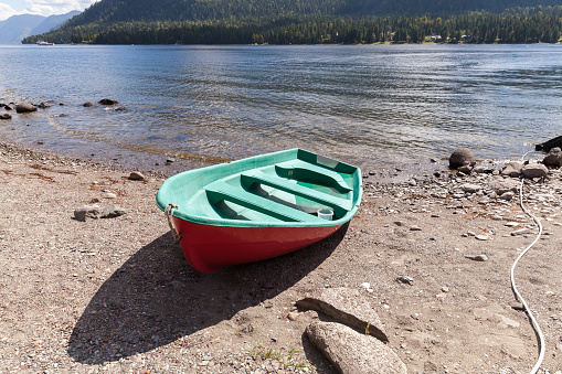 Row boat is  on a coast of the Teletskoye lake on a sunny summer day. Siberian landscape