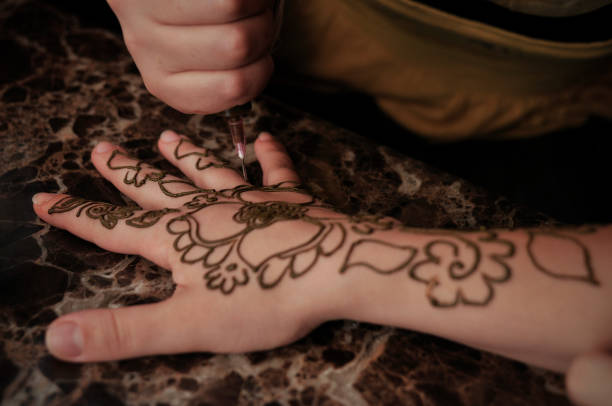 A temporary tattoo is drawn on the hand with henna.
