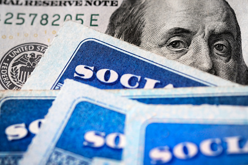 Several Social Security Cards on a US United States one hundred dollar bill $100 system of benefits for retired elderly people