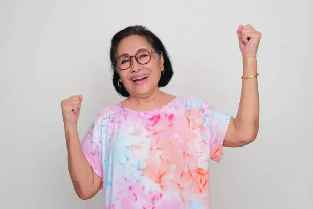 Asian elderly women cheering happily with both hand clenched in the air