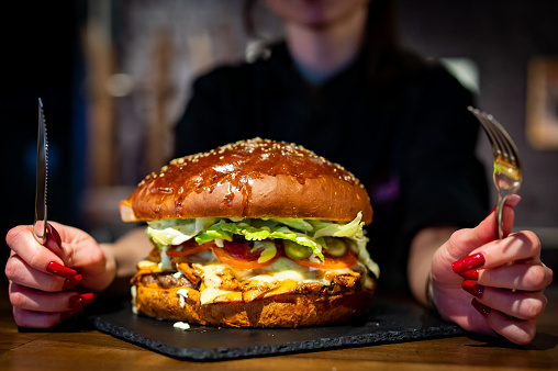 woman with fork and knife with very big large burger