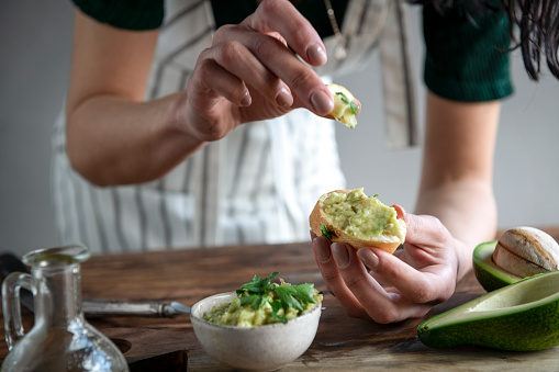 Female hands making avocado sandwich