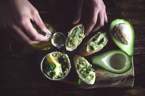 Female hands making avocado sandwich