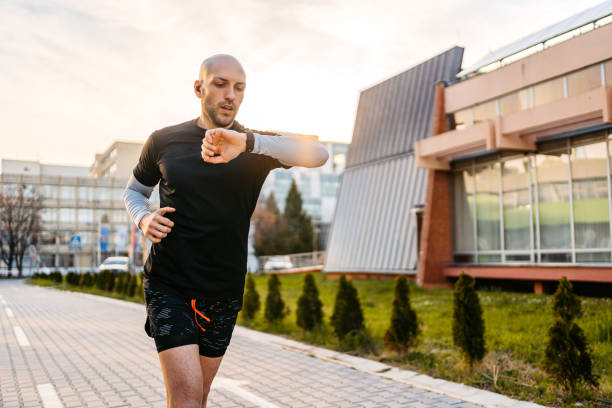 athleten, die ihre fitnessaktivität auf dem fitness-tracker überprüfen, während sie im freien laufen - gps watch stock-fotos und bilder