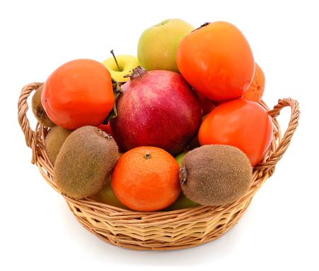 Tangerines, pomegranate and kiwi in a basket isolated on a white background.