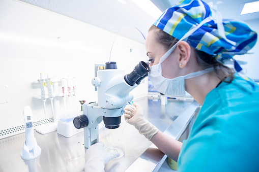 Young african american woman scientist using microscope write on document at laboratory