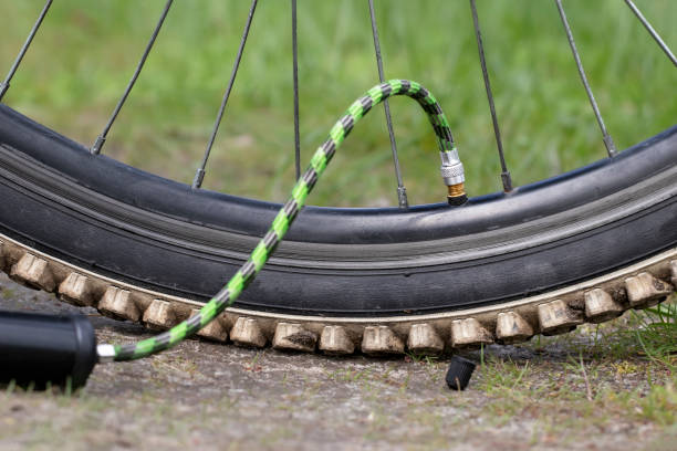 close-up da válvula de enchimento do pneu da bicicleta. válvula da bomba conectada à roda. - bicycle bicycle pump inflating tire - fotografias e filmes do acervo