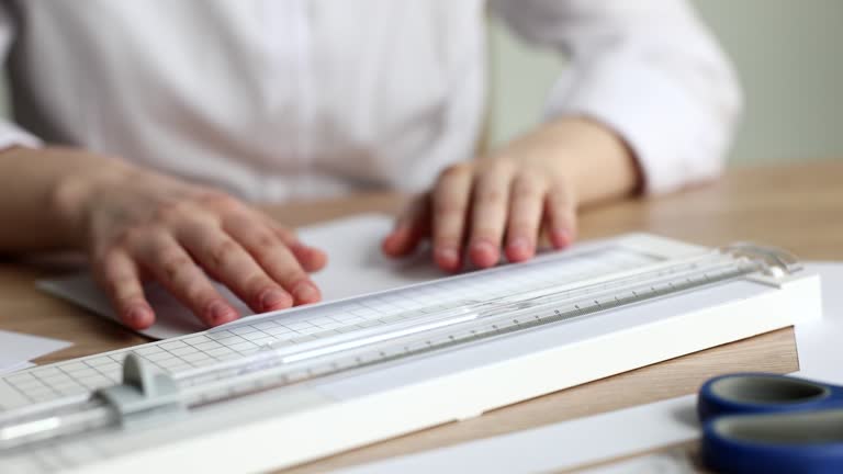 Woman hands cutting drawing with paper knife paper knife with ruler guillotine closeup 4k movie slow motion