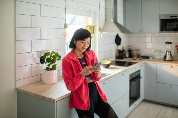 istock Young adult woman using a smart phone in a kitchen 1485794256