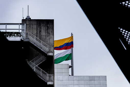 Colombian and Antioquia flags waving in the wind from the top of a building where the emergency exit stairs can be seen.