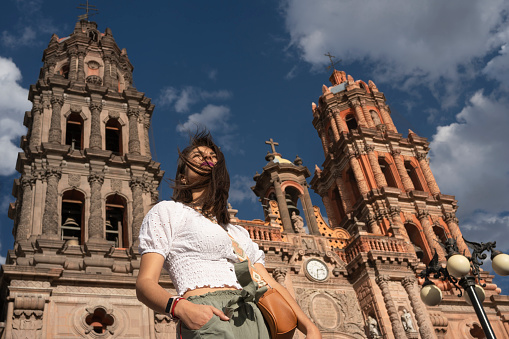 portrait of latin woman with wind on her face in the cathedral of San Luis Potosi in the background