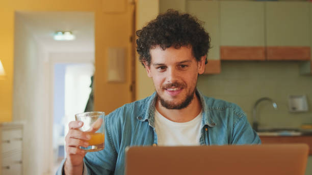 istock Guy dressed in denim shirt works on laptop while having lunch in cozy kitchen 1485808285