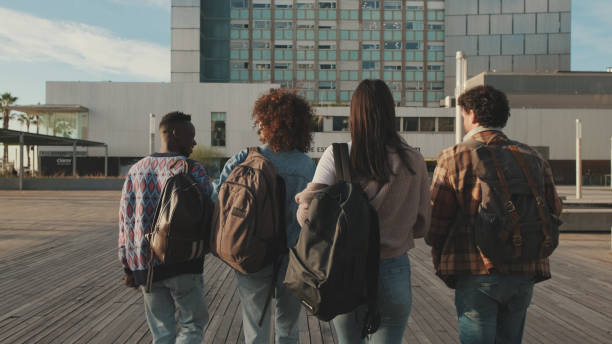 istock Group of students are walking from outside. Classmates students walk down the street talking and laughing together. Back view 1485808427