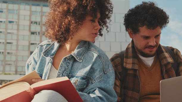 istock Student couple studying while sitting outside the university building 1485808490