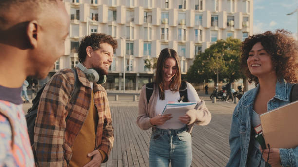 istock Group of students are chatting while standing outside. Cheerful students are talking and laughing standing outside with books 1485808641