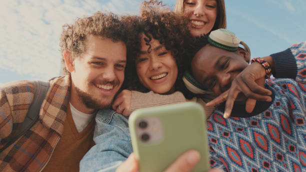 istock Happy smiling friends make a video call from a mobile phone. Four students wave their hands in greeting 1485808705