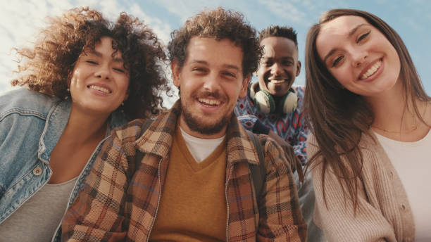 istock Happy smiling friends make a video call from a mobile phone. Four students wave their hands in greeting 1485808718