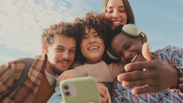 istock Happy smiling friends make a video call from a mobile phone. Four students wave their hands in greeting 1485808720