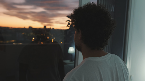 Close-up of young man looking out the window at the sunset