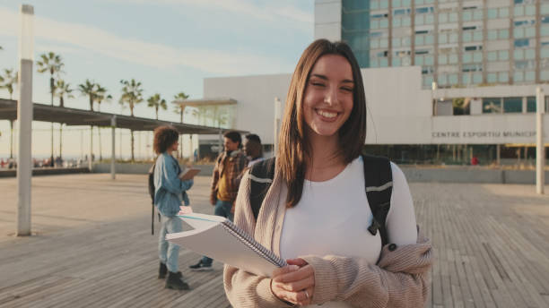 istock Girl is smiling while looking at the camera. Student with notebooks in her hands looks at the camera and smiles 1485808850