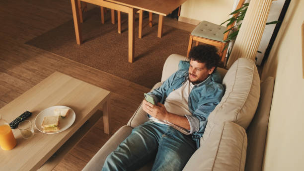 istock Happy guy holds smartphone in his hands, sends text message, communicates in social networks, surfs the web while sitting indoors 1485808907