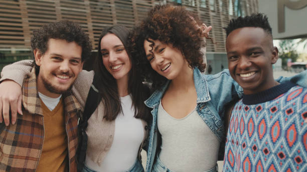 istock Close up, young smiling people posing while standing on the street. Four students look at the camera and smile. 1485809155