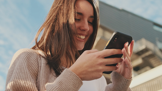 Close-up of a young woman using a mobile phone. Portrait of a happy girl typing a social media message on her mobile phone