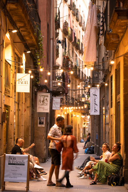 群衆はバルセロナスペインのバリオゴティックの狭い通りの店を通り過ぎます - gotic ストックフォトと画像