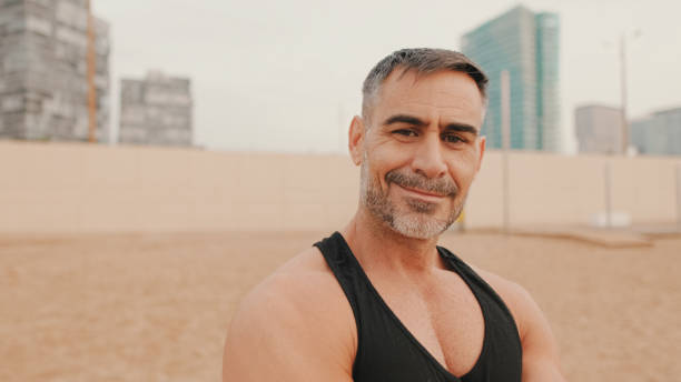 istock Close up, middle aged athletic man smiling and looking at camera while standing on the beach 1485810371