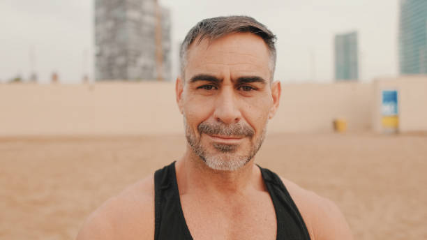 istock Close up, middle aged athletic man smiling and looking at camera while standing on the beach 1485810400
