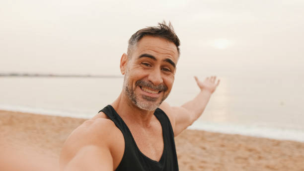 istock Middle-aged athletic man stands on the beach after workout and makes video call with mobile phone 1485810539