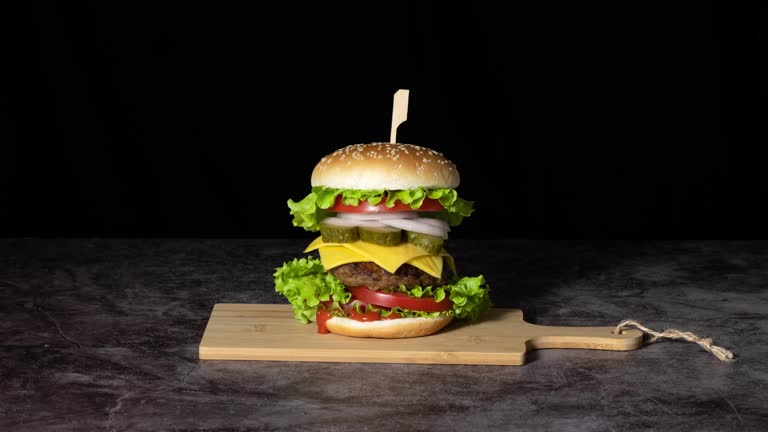 Making a hamburger, side view of assembling ingredients. Stop motion animation.