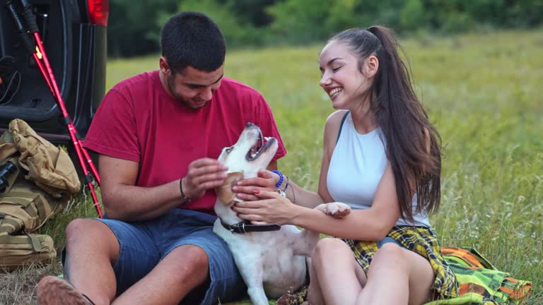 Young cheerful couple petting their dog outdoors