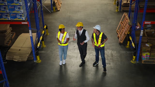 Managers and employees walk to check stock on shelves in a warehouse.