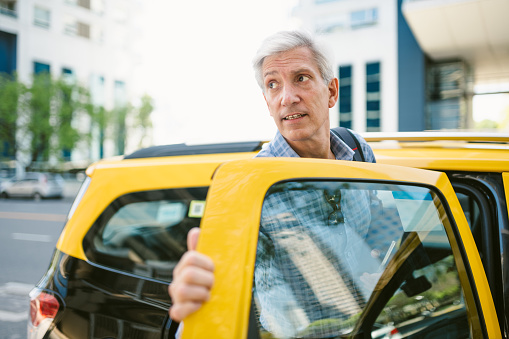 Mature businessman opening the door of a taxi
