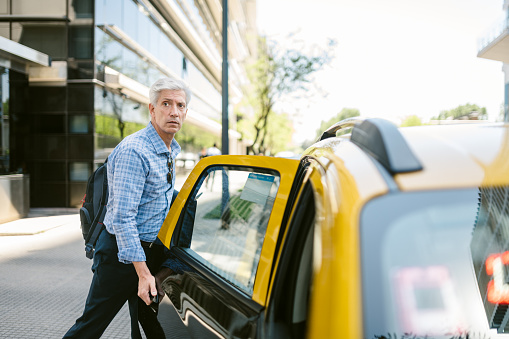 Mature businessman opening the door of a taxi